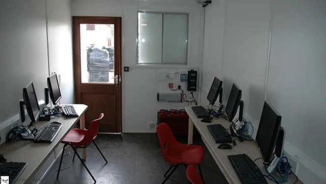 Makeshift dev office with kid-sized red chairs and tightly packed workstations
